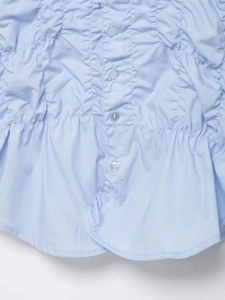 Detailed view of light blue smocked shirt featuring tonal buttons and ruffled hemline