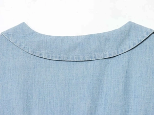 Close-up of the pleated round neckline and neat stitching on light blue denim fabric