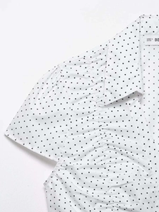 Detail of white short sleeve shirt with black polka dots and elegant ruffled front design