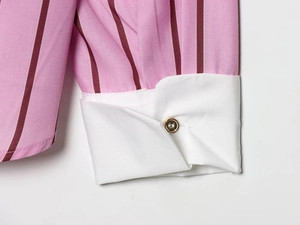 Detail of pink striped shirt sleeve with white contrast cuff and golden button