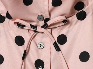 Detailansicht der rosa gepunkteten Jacke mit grauen Knöpfen und Taillenkordelzug