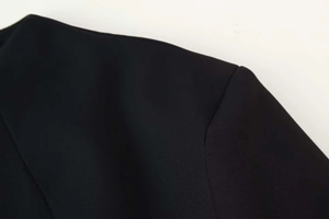 Détail de la couture d'épaule précise et du tissu tissé noir de la robe