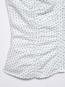 Close-up of white polka dot blouse featuring ruching details and clear button