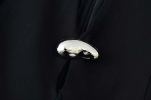 Détail d'un bouton métallique argenté chic sur une robe noire cintrée élégante