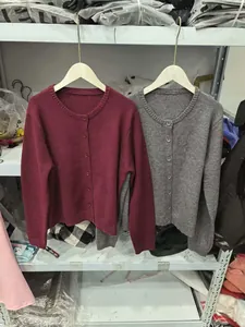 Detail of round neck knit cardigan with matching buttons in burgundy and grey