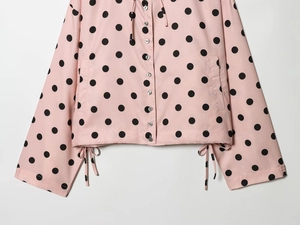 Detail der rosa gepunkteten Jacke mit Kordelzug am Saum und vorderer Knopfleiste