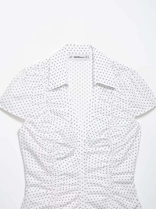 Detail of white short sleeve shirt with black polka dots, V-neckline and decorative ruching