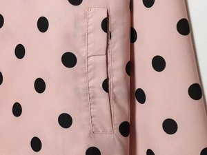 Detailansicht einer Paspeltasche auf einer rosa Jacke mit schwarzen Polka-Dots