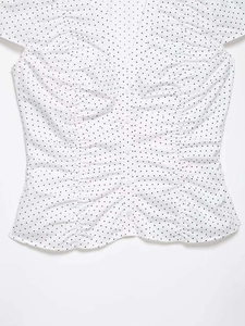 Close-up of retro white polka dot shirt featuring ruched front and elegant button detail