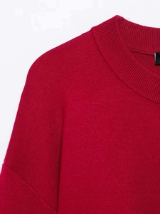 Detailed view of the red knit sweater showing the round ribbed neckline and fine fabric