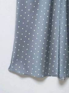 Dettaglio del tessuto in raso azzurro a pois bianchi con finitura dell'orlo cucito