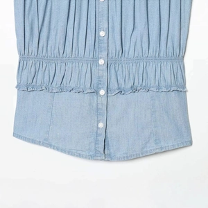 Short sleeve light blue denim shirt with white buttons and waist pleats on white background
