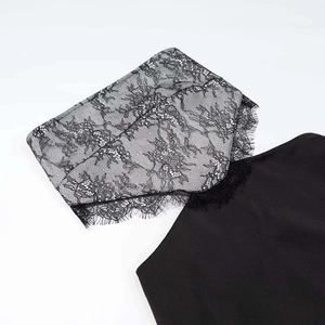 Close-up of intricate black floral lace with eyelash trim on backless summer dress