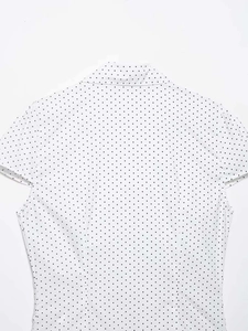 Detail view of the black polka dot pattern and precise stitching on the white short sleeve shirt