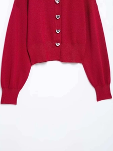 Detailed macro view of heart-shaped silver metal buttons on a red knit cardigan