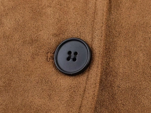 Détail d'un trench-coat en daim marron avec bouton noir à quatre trous et surpiqûres