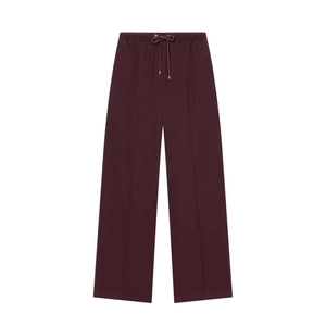 Detail of dark red wide-leg trousers featuring drawstring waist and front seam