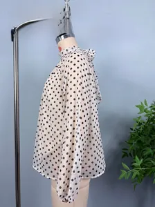 Detailed side view of a vintage polka dot chiffon blouse with a high neck and cuffed sleeves