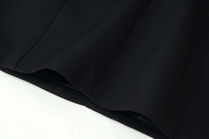 Gros plan sur la texture du tissu noir avec poche et coutures verticales de la robe cintrée