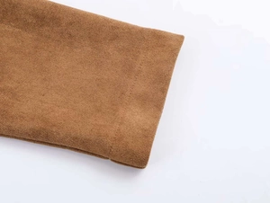 Détail macro du tissu en daim marron montrant la texture fine et les coutures du poignet