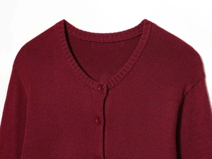 Close-up of ribbed crewneck and button closure on wine red knitted cardigan