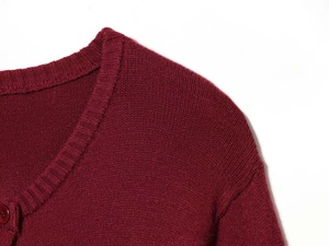 Close-up of wine red knit cardigan featuring a ribbed crew neck and fine texture detail