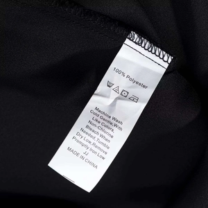 Detailed macro view of the 100% polyester fabric care label on a black lace dress