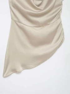 Detail of champagne satin top featuring cowl neck and asymmetrical pointed hemline