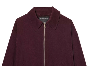 Detail of burgundy wool blend jacket collar with metal zipper and premium fabric texture