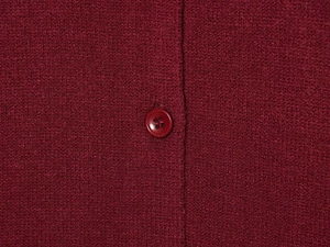 Close-up of deep red knit cardigan showing fabric texture and matching button detail