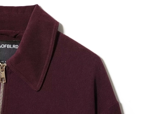 Detail of burgundy knitted jacket collar with golden zipper and brand neck label