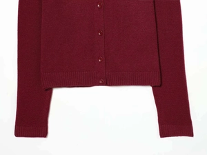 Detail view of burgundy knit cardigan featuring matching buttons and ribbed cuffs
