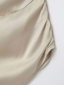 Detailed view of champagne satin fabric with ruching and smooth silk texture