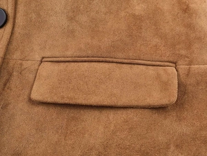 Détails du manteau en daim marron montrant les coutures de la poche et le bouton noir