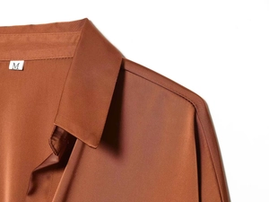 Detail of satin shirt collar and shoulder seam in caramel brown with size M tag