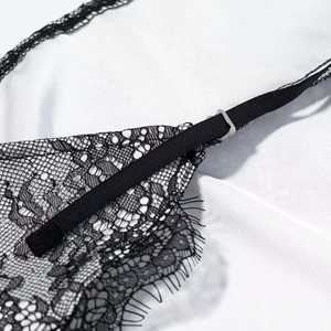 Detail view of adjustable strap with metal buckle on black eyelash lace dress