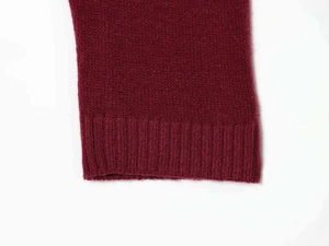 Detail of burgundy knitted cardigan featuring ribbed cuffs and soft textured fabric