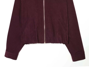 Detail of burgundy zip-up jacket showing textured knit fabric and metal zipper