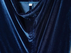 Gros plan de la texture en velours bleu foncé et de l'étiquette de taille S sur la robe