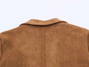 Détail du col à revers et des coutures sur un manteau vintage marron en suédine