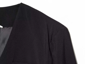 Detail of V-neck suit romper featuring sharp tailoring and premium textured black woven fabric