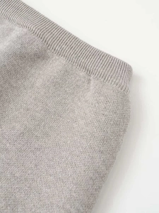 Detailed close-up of light grey ribbed elastic high waistband on fine knit skirt