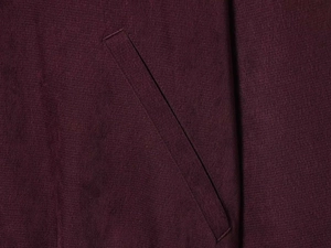 Macro shot of the side pocket and fine stitching on deep burgundy knit fabric pants