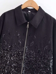 Detailed view of the dense black sequin decoration and silver zipper on the jacket