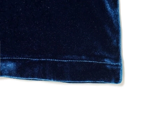 Détail de la texture du velours bleu marine avec couture d'ourlet propre sur la robe