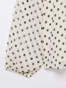 Detailed macro view of polka dot chiffon fabric showing elastic cuff and subtle texture