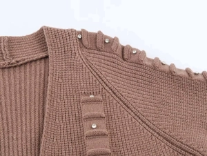 Close-up of thick ribbed knit cardigan with sparkling rhinestone detail on the tan fabric