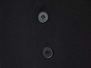 Close-up of black suit fabric texture and matching four-hole buttons on a V-neck romper