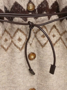 Detail view of vintage jacquard knit cardigan with amber buttons and waist belt