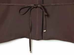 Macro detail of dark brown satin shirt featuring a slim tie with gold metal tips